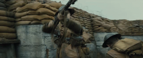 Soldier Holding Gun In Front Of Sandbag Wall GIF