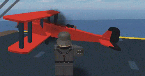 A Soldier Is Standing Next To A Red Airplane On A Runway . GIF