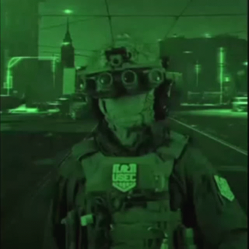 A Soldier Wearing A Helmet And Goggles Is Standing In A Dark Street At Night . GIF