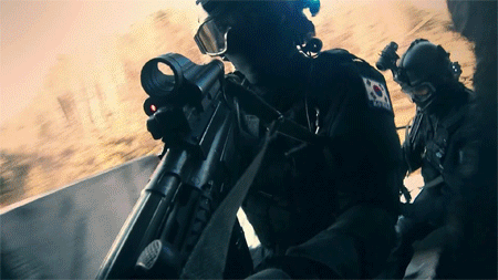 A Soldier With A Korean Flag On His Back Holds A Rifle GIF