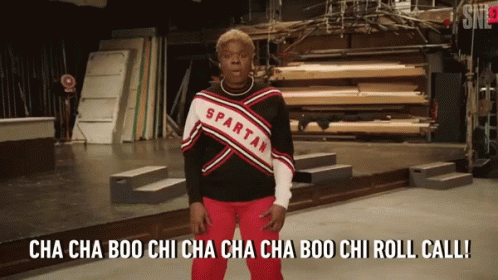 A Spartan Cheerleader Is Standing On Stage GIF