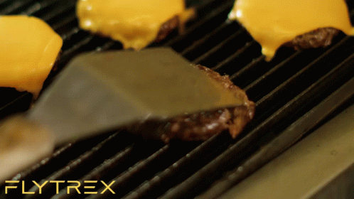 A Spatula Is Being Used To Turn A Hamburger On A Grill With Flytrex Written In The Upper Right Corner GIF