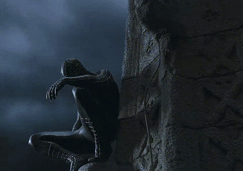 A Spider Man In A Black Suit Is Covering His Face GIF