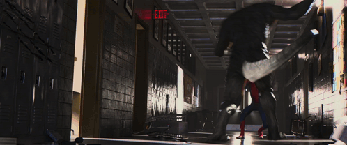 A Spider Man Is Standing In A Hallway With A Red Exit Sign GIF