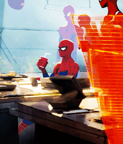 A Spider Man Sitting At A Table Holding A Cup Of Coffee GIF