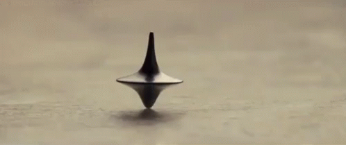 A Spinning Top Is Spinning On A Table In A Black And White Photo . GIF