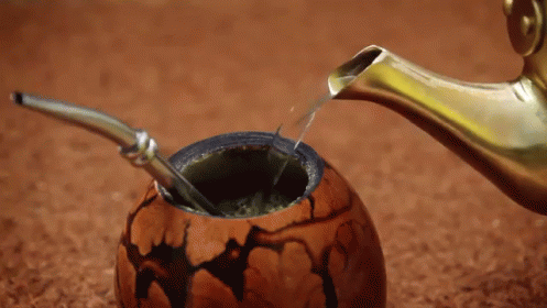 A Spoon Is Being Used To Pour Liquid Into A Bowl GIF