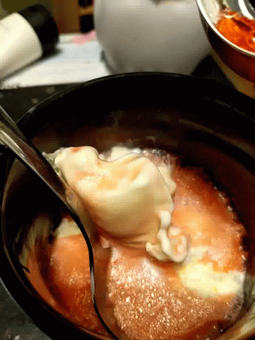 A Spoon Is Stirring A Sauce In A Pot GIF