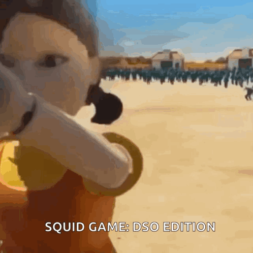 A Squid Game Doll Is Standing In Front Of A Group Of People . GIF