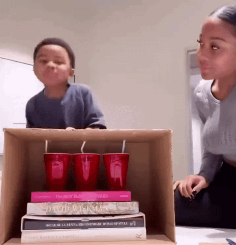 A Stack Of Books Including Oscar De La Renta 'S Legendary World Of Style Sit On A Cardboard Box GIF