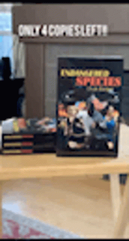 A Stack Of Books Sitting On Top Of A Wooden Table With A Sign That Says Only 4 Copies Left . GIF