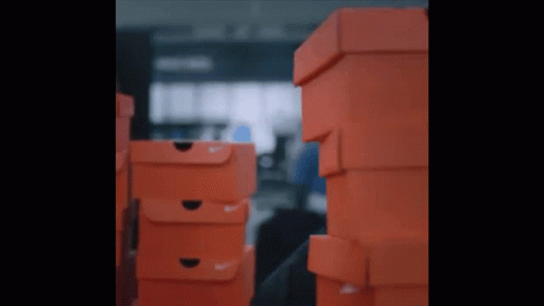 A Stack Of Orange Nike Boxes In A Dark Room GIF