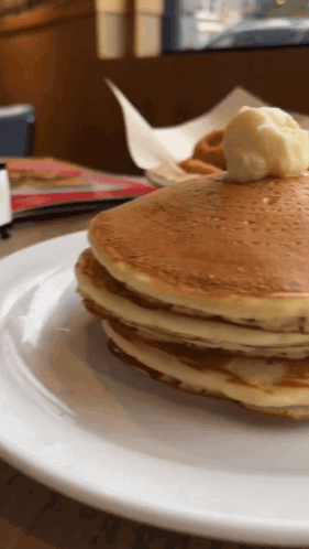 A Stack Of Pancakes On A Plate With Butter On Top GIF