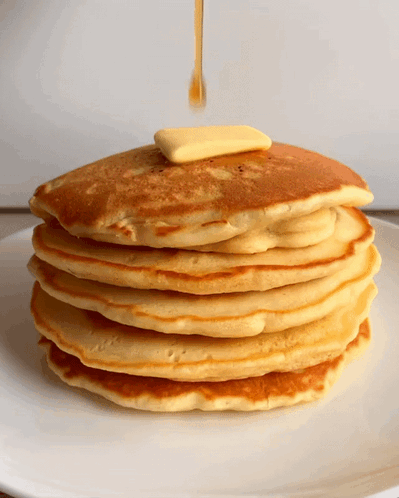 A Stack Of Pancakes With Syrup And Butter Being Poured On Top GIF