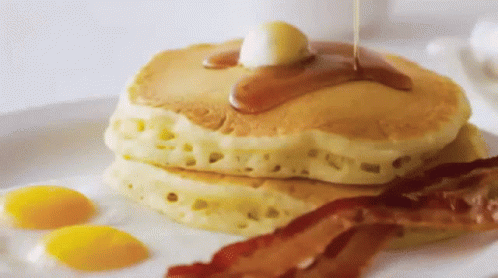 A Stack Of Pancakes With Syrup Being Poured On Them GIF