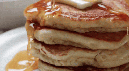 A Stack Of Pancakes With Syrup Being Poured On Them GIF