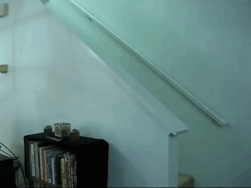 A Staircase With A Bookshelf Underneath It And A White Railing GIF