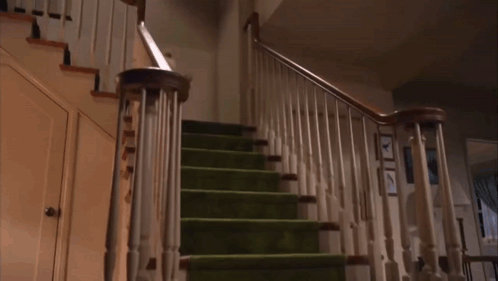 A Staircase With Green Carpeted Steps And A White Railing GIF