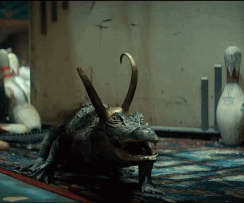 A Statue Of A Crocodile With A Bowling Pin In The Background .. GIF