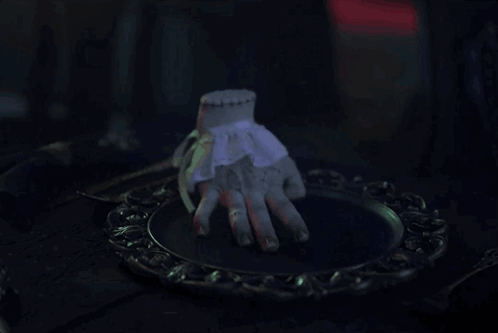 A Statue Of A Hand Is Sitting On A Plate GIF