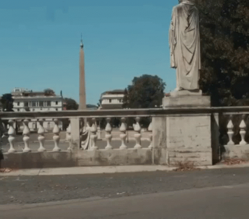 A Statue Of A Man In A Robe Is On A Bridge GIF