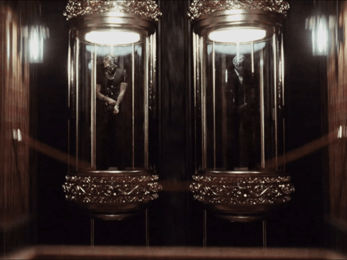 A Statue Of A Man In A Suit Is Displayed In A Glass Case GIF