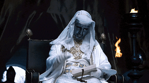 A Statue Of A Man In A White Robe Is Reading A Book GIF