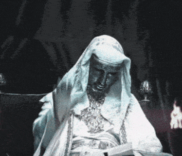 A Statue Of A Man In A White Robe Waves His Hand GIF