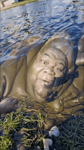 A Statue Of A Man Laying In The Water GIF