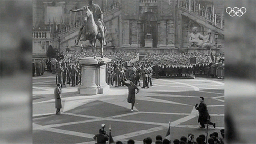 A Statue Of A Man Riding A Horse Is In Front Of A Crowd Of People GIF