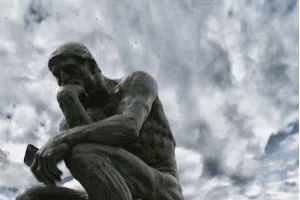 A Statue Of A Man Sitting Down Thinking With A Phone In His Hand . GIF