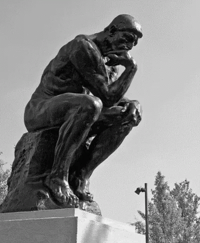 A Statue Of A Man Sitting On A Rock With His Hand On His Chin GIF