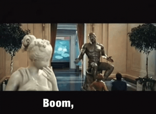 A Statue Of A Man Sitting On A Throne Next To A Woman And The Words Boom GIF
