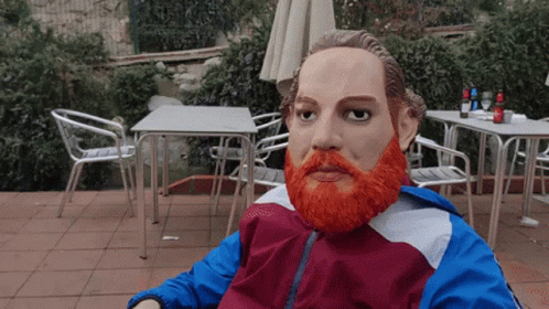 A Statue Of A Man With An Orange Beard Is Sitting In A Chair GIF