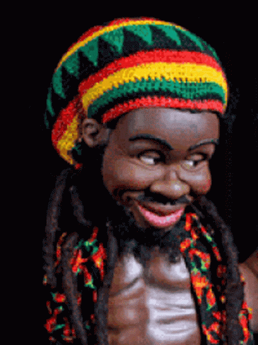 A Statue Of A Man With Dreadlocks And A Colorful Hat GIF