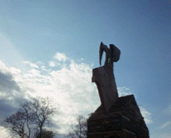 A Statue Of A Man With Wings Standing On Top Of A Building GIF