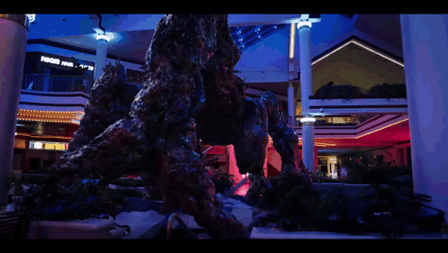 A Statue Of A Monster In A Mall With A Sign That Says ' A & R ' On It GIF