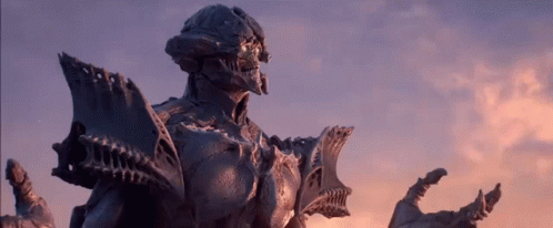 A Statue Of A Monster Is Standing In Front Of A Sunset Sky GIF
