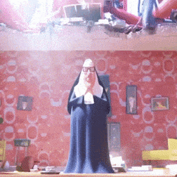 A Statue Of A Nun Is Standing In Front Of A Wall With A Pattern Of Circles GIF