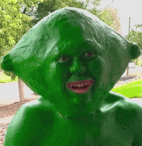 A Statue Of A Person With A Green Head And Red Eyes GIF