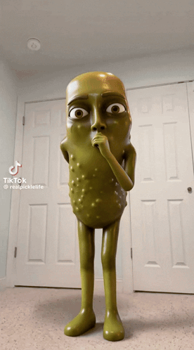 A Statue Of A Pickle With A Surprised Look On His Face Is Standing In Front Of A Door GIF