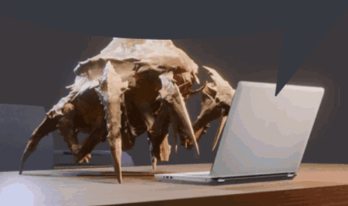 A Statue Of A Spider Looking At A Laptop GIF