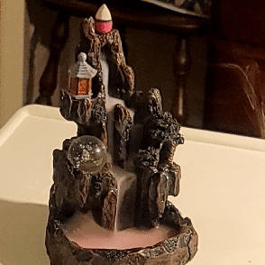 A Statue Of A Waterfall Is Sitting On A White Table GIF