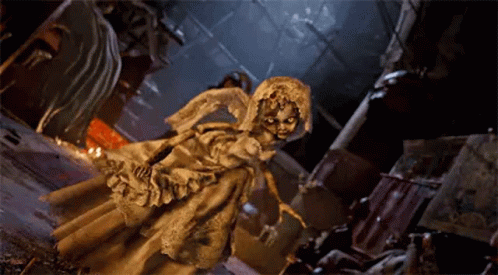A Statue Of A Woman In A White Dress And Veil Is Standing In A Dark Room . GIF