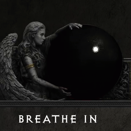 a statue of an angel holding a red ball with the words breathe out underneath it