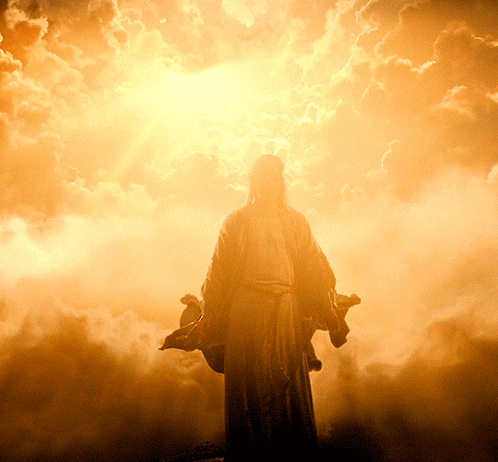 A Statue Of Jesus In A Cloudy Sky With The Sun Behind Him GIF
