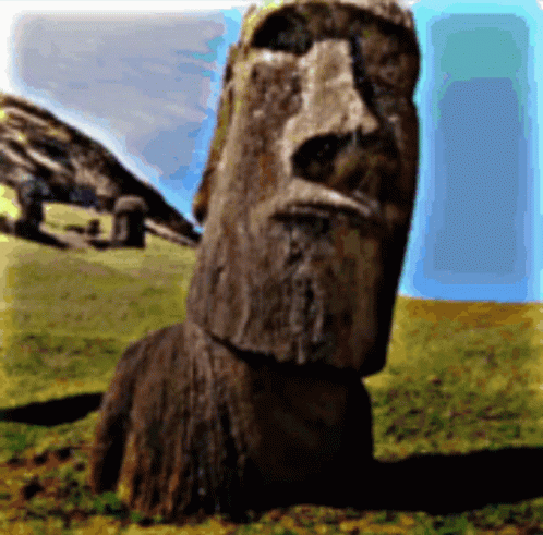 A Statue With A Face Carved Into It Is Sitting In A Grassy Field GIF