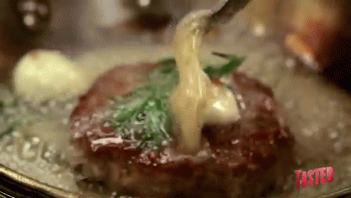 A Steak Is Being Cooked In A Pan With A Fork And Sauce Being Poured Over It . GIF