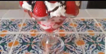 A Strawberry Sundae With Whipped Cream And Chocolate Sauce In A Glass On A Table . GIF