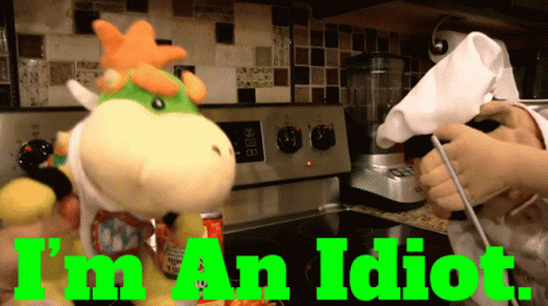 A Stuffed Animal In A Kitchen With The Words " I 'M An Idiot " Above It GIF